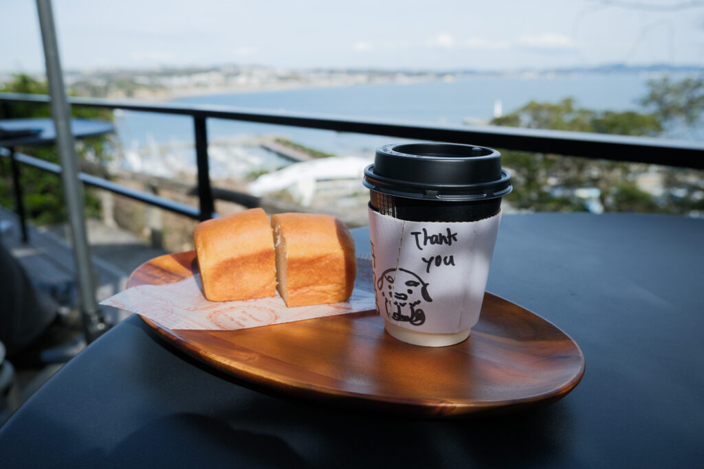 海を見下ろすテラス席に置いたパンとコーヒー