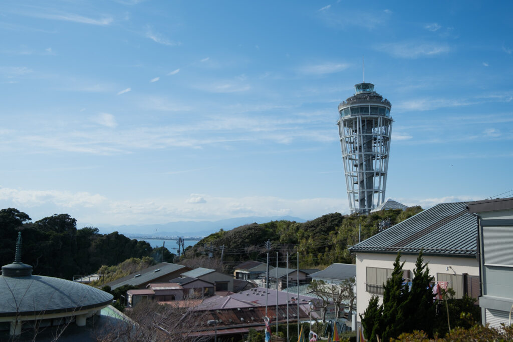 家々の屋根の向こうに立つ江の島シーキャンドル