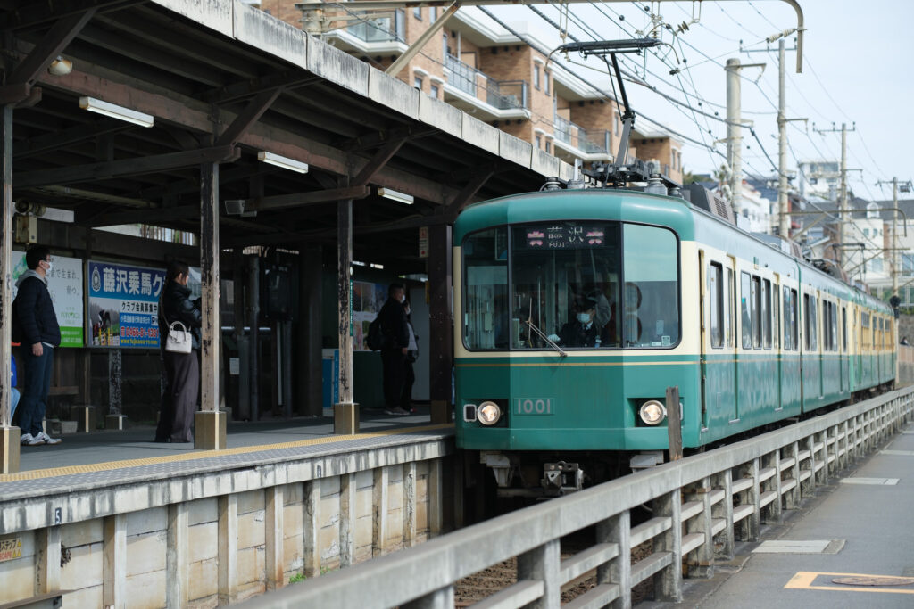 鎌倉高校前駅に到着する緑とクリーム色の江ノ電