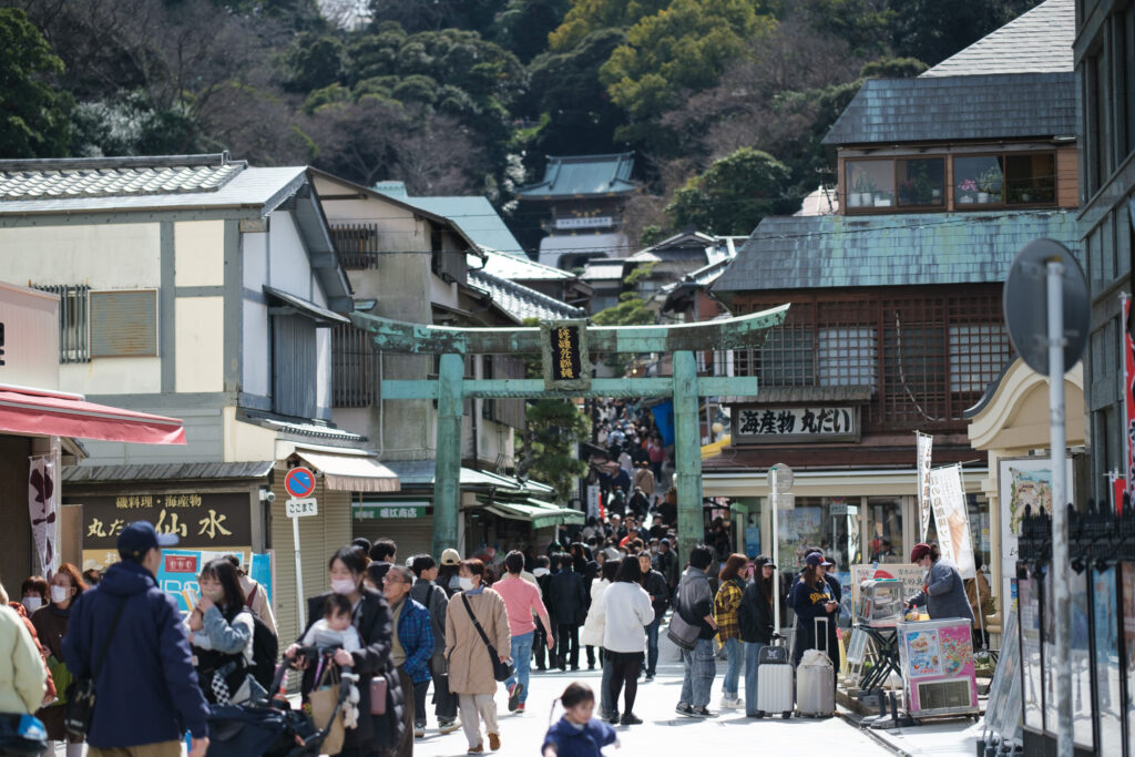 江の島の入口にある青銅の鳥居と、観光客でにぎわう参道