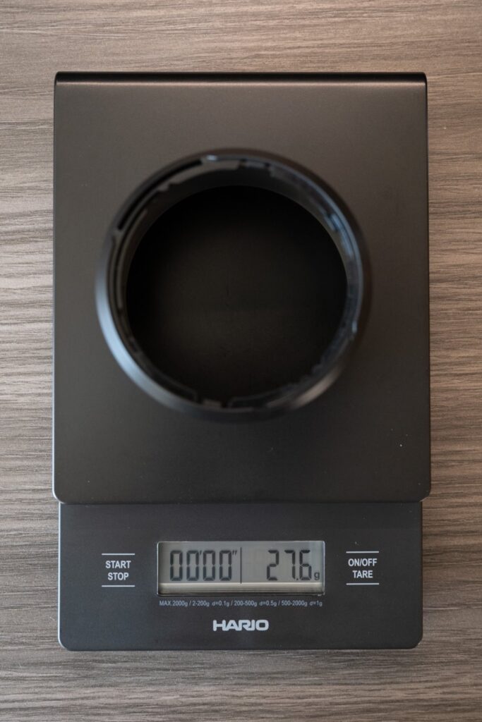 量りに載せた XF33mmF1.4 の付属フード。27.6g